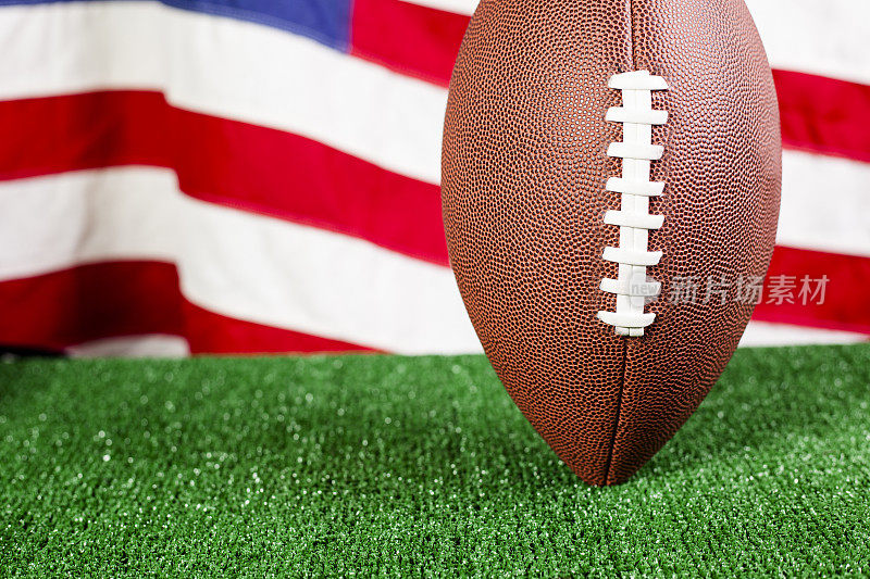 在带有美国国旗的绿色草地上的美式足球。