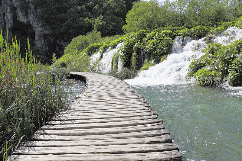 穿过小瀑布进入克罗地亚Plitvice池塘的木制小路