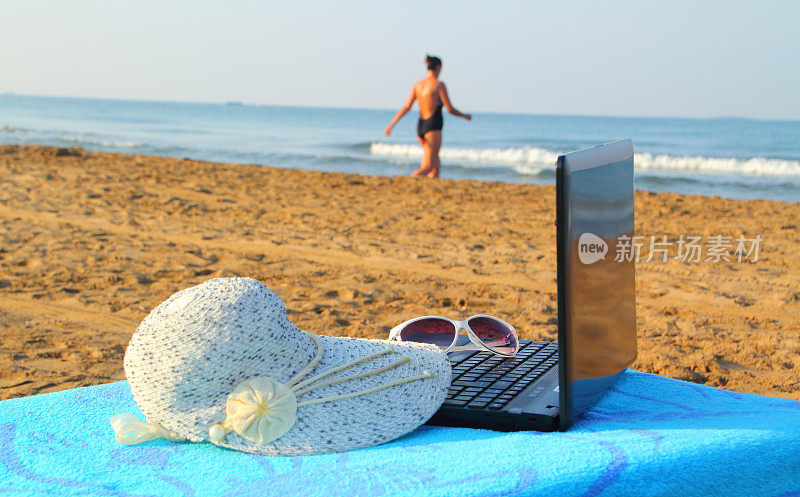 笔记本电脑和太阳帽在海滩上