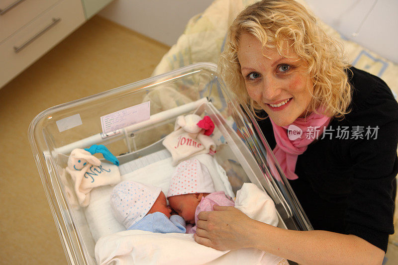 微笑的母亲和刚出生的双胞胎在医院