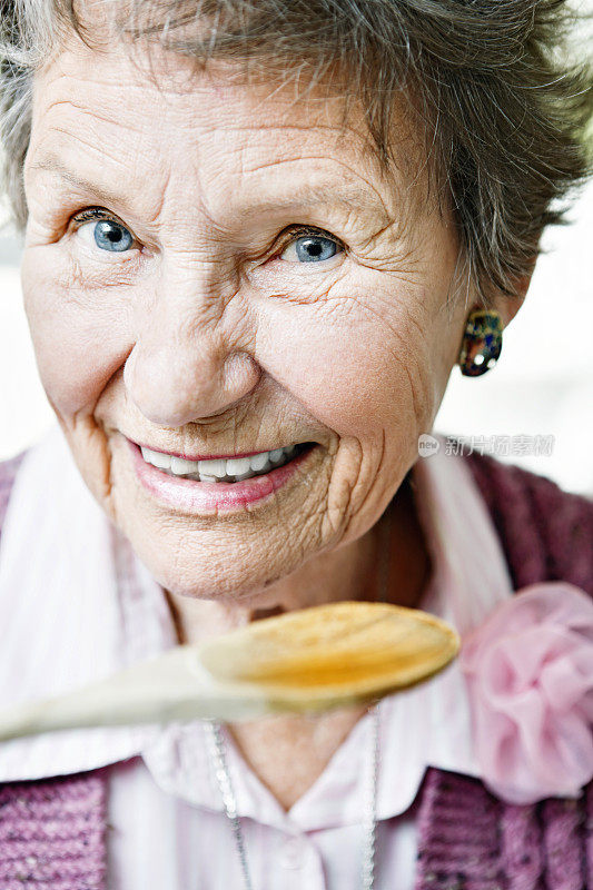 80岁的女人微笑着品尝木勺