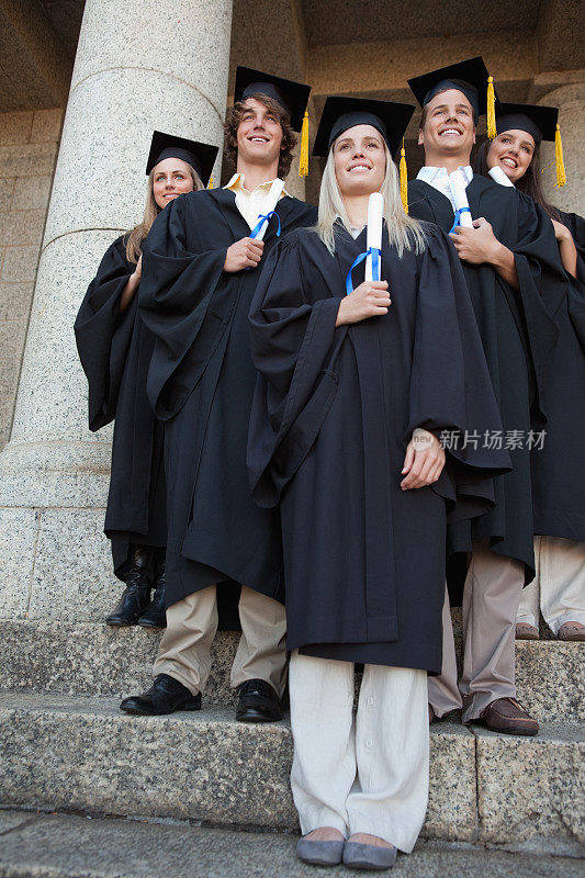 年轻的毕业生微笑着站在他们的di