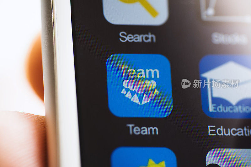 手持手机，屏幕上的团队应用程序图标