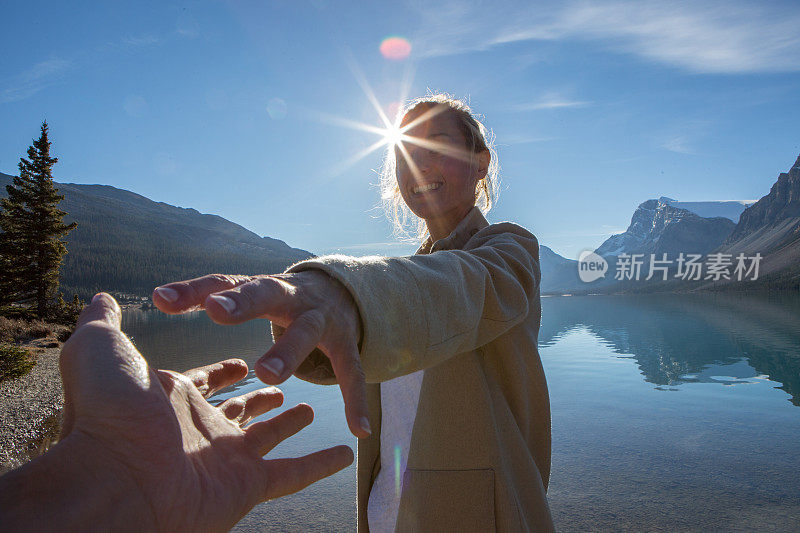 日出时分，一对年轻夫妇手牵着手沿着湖岸散步