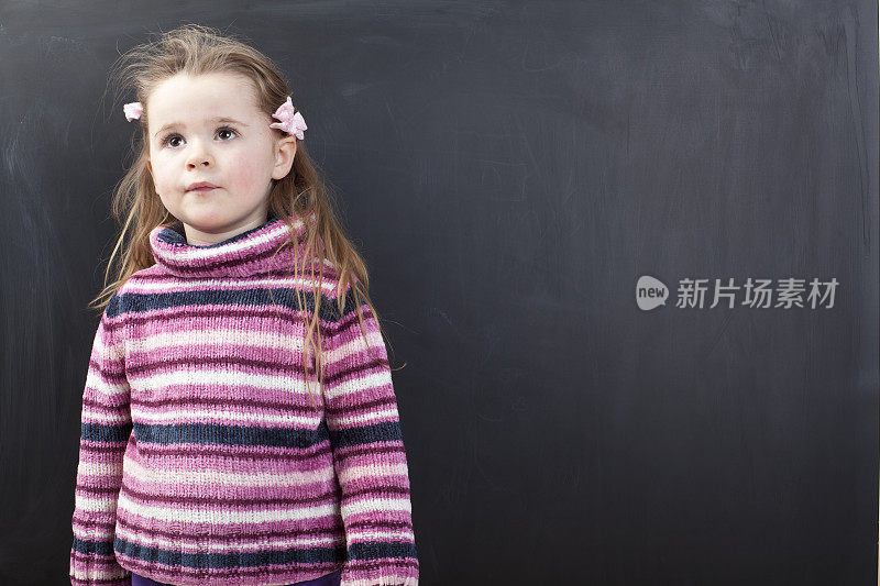 可爱的女孩站在黑板前