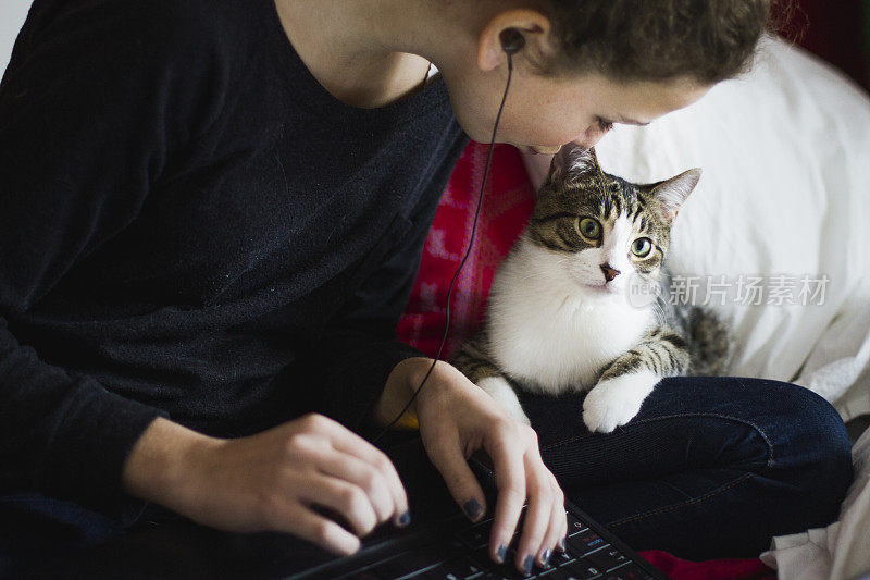 一个十岁的女孩在用笔记本电脑，旁边有一只猫