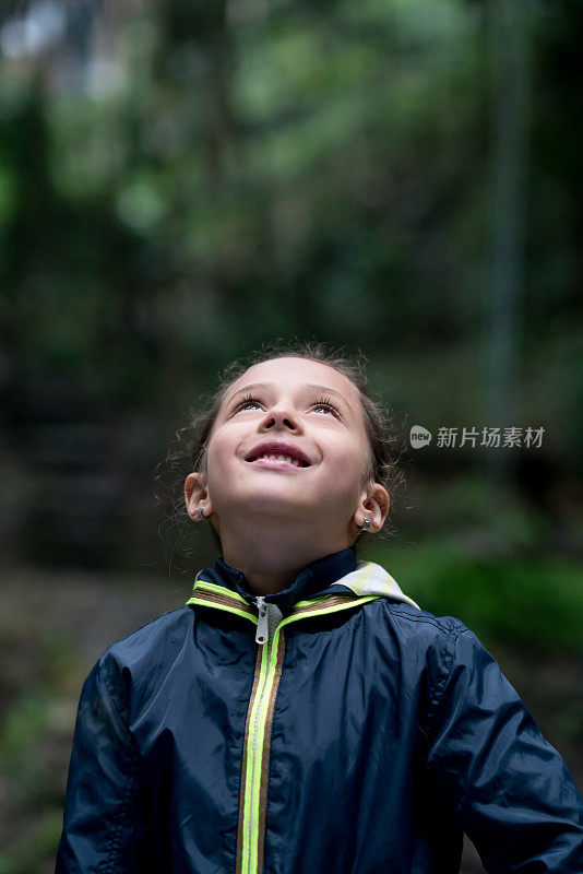 一个快乐的女孩抬头望向户外的肖像