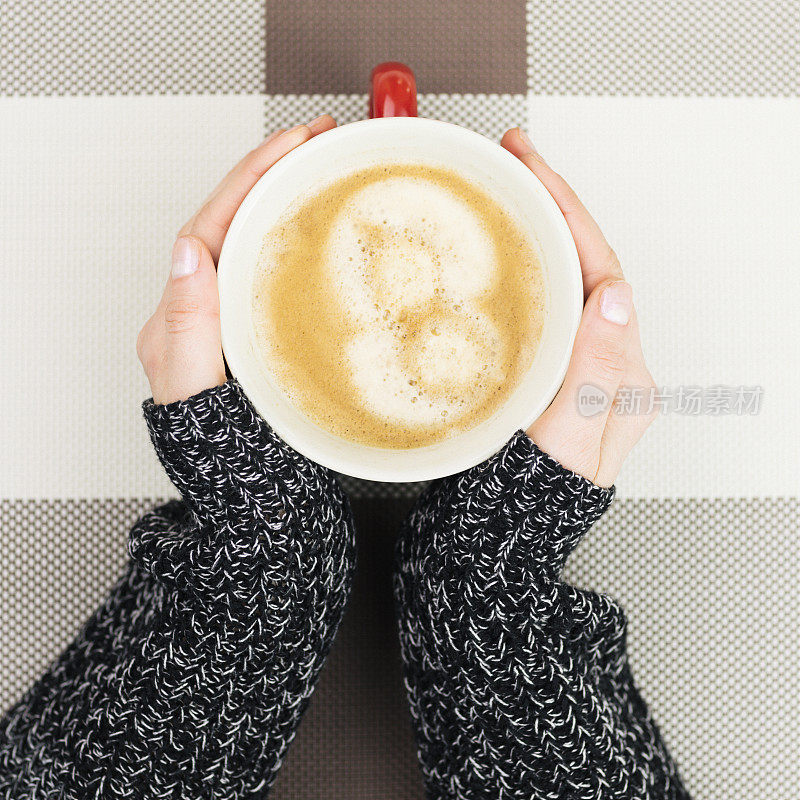 女人在咖啡杯旁暖手