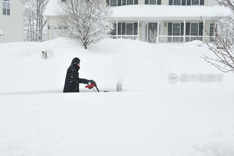 男人在齐腰深的雪中推着除雪机