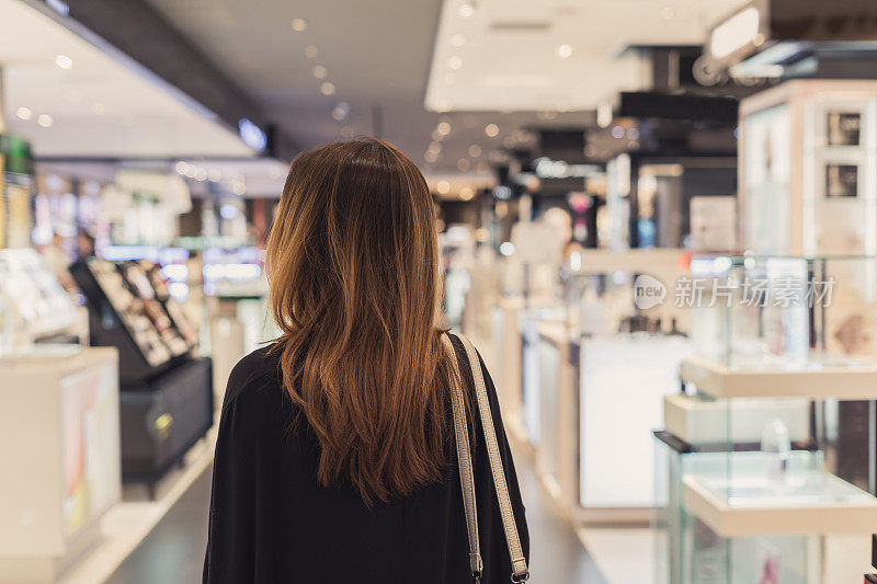 年轻的亚洲女人走在化妆品部在购物中心