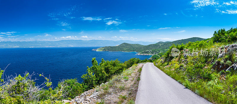 美妙浪漫的夏日午后景观全景海岸线亚得里亚海。沿海岸的悬崖上有一条狭窄的山路。海湾里清澈湛蓝的水。Krk岛。克罗地亚。欧洲。