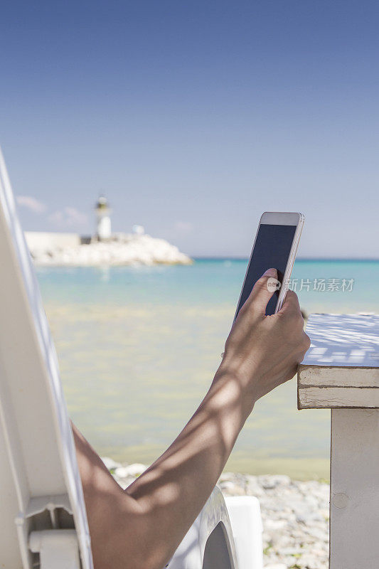 一个在海滩上玩智能手机的女人