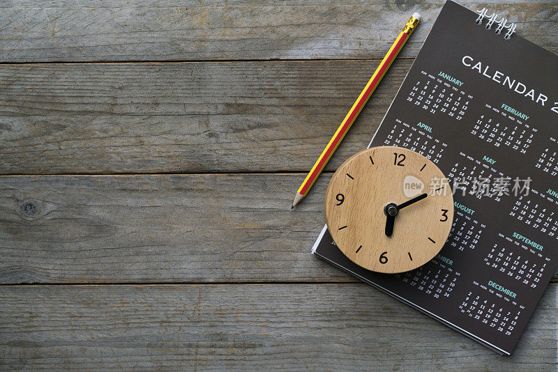 靠近时钟，日历和铅笔在桌子上，计划商务会议或旅行计划的概念