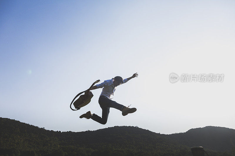 年轻有权势的男人拿着吉他在球场上跳来跳去