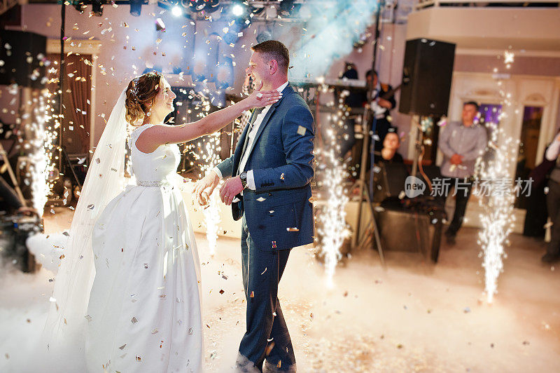 新婚夫妇在他们的婚礼上以浓烟、彩灯和烟火为背景跳舞。