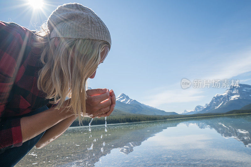 年轻女子的近距离饮用新鲜的水从山湖