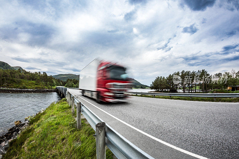 一辆油罐车在挪威高速公路上飞驰。运动模糊的卡车。