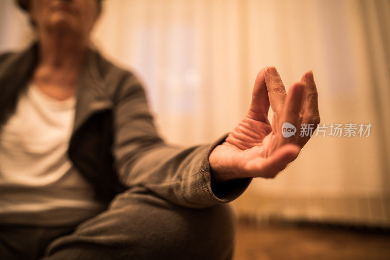 年长妇女在家里练习瑜伽的特写。