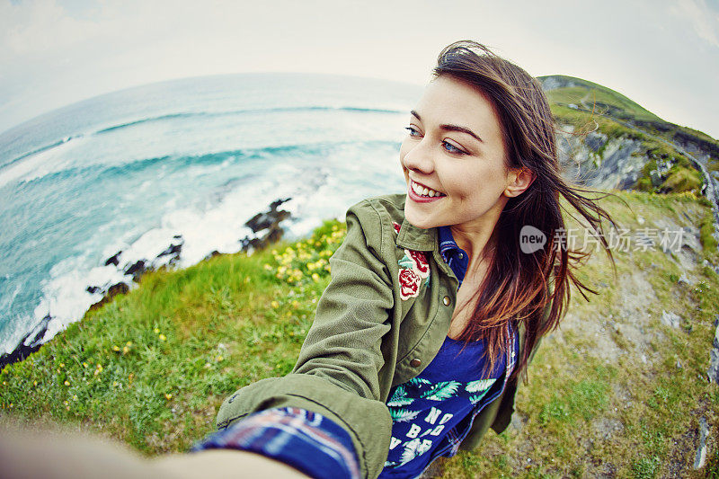 鱼眼镜头的快乐女人自拍悬崖上的海上