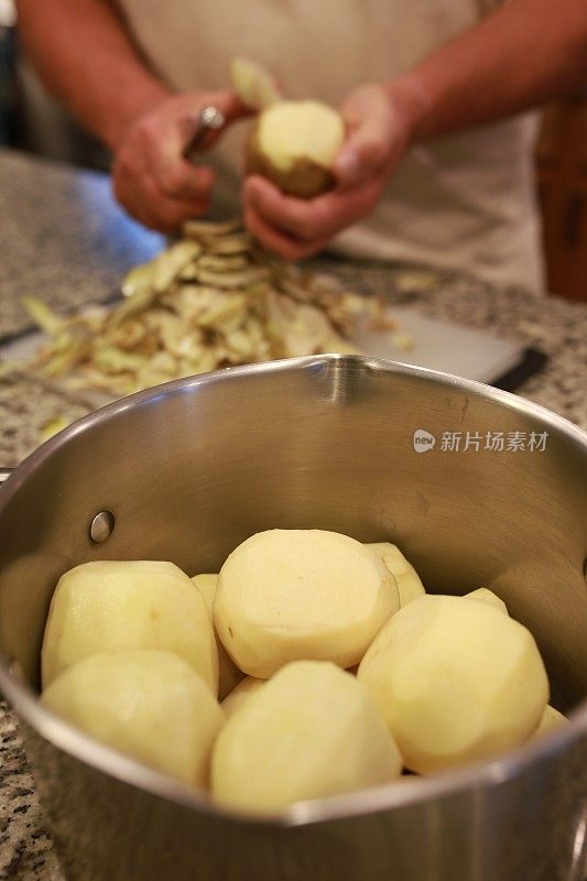 男厨师手削皮准备土豆在锅里煮