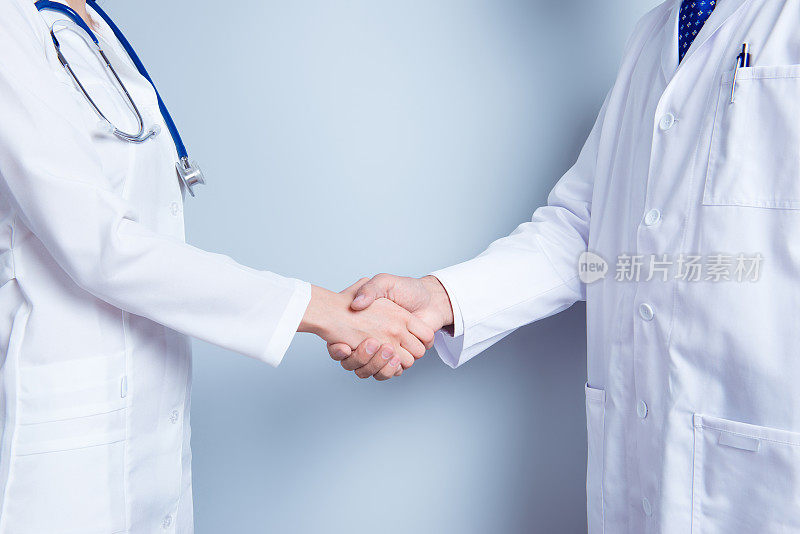 交易!医学合作的概念。特写照片的两个医生握手的灰色背景