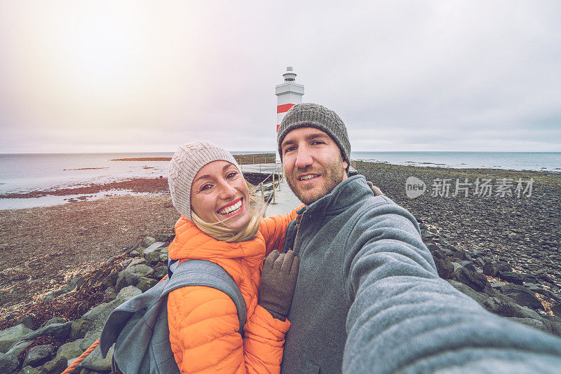 旅游情侣在灯塔自拍，冰岛-人们旅游有趣的北方国家概念