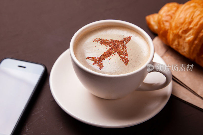 一杯泡着飞机的咖啡。飞机上的早餐咖啡和牛角面包