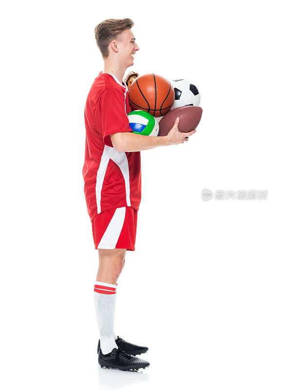 白人年轻男子足球运动员站着，戴着棒球手套，拿着篮球，踢足球和使用运动球
