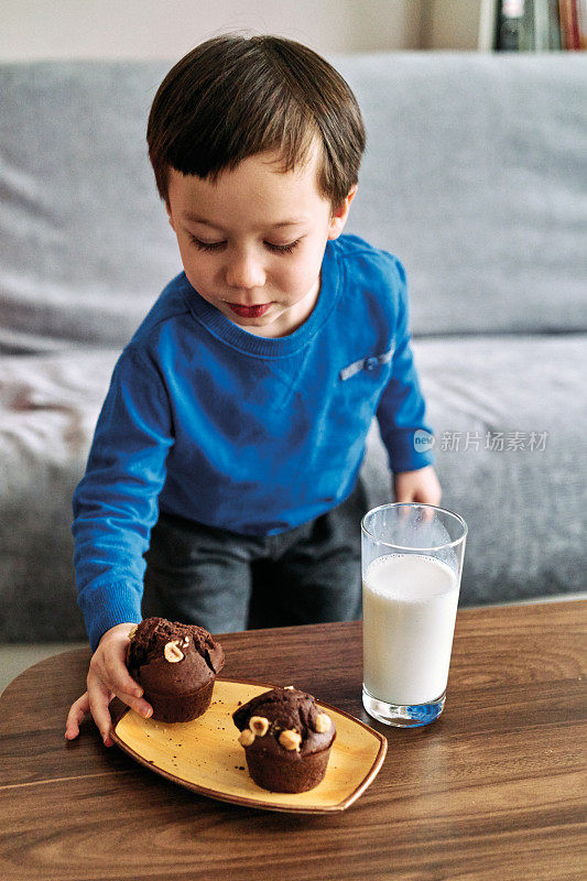 2-3岁可爱的孩子喝牛奶吃蛋糕。他喜欢牛奶。