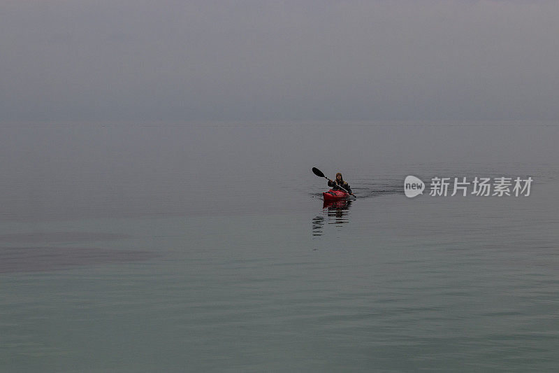 女人划着皮艇在空旷的海面上