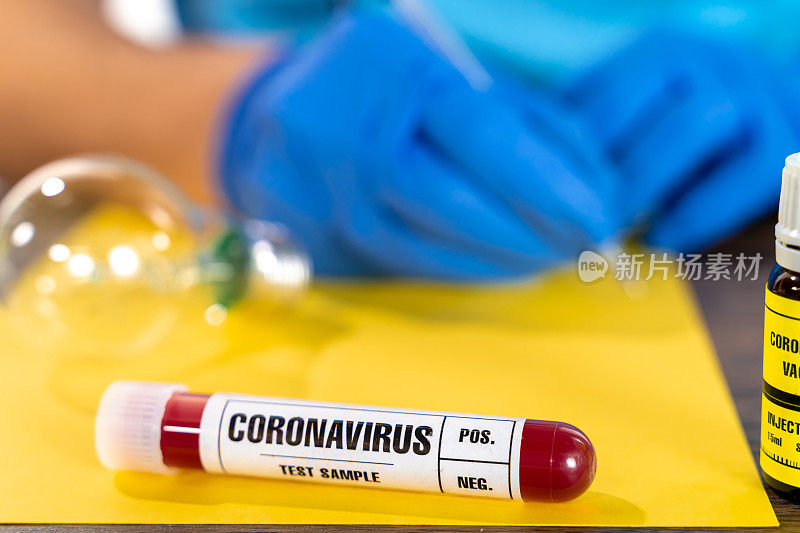 医生在黄色纸上写着COVID-19血液样本试管，特写