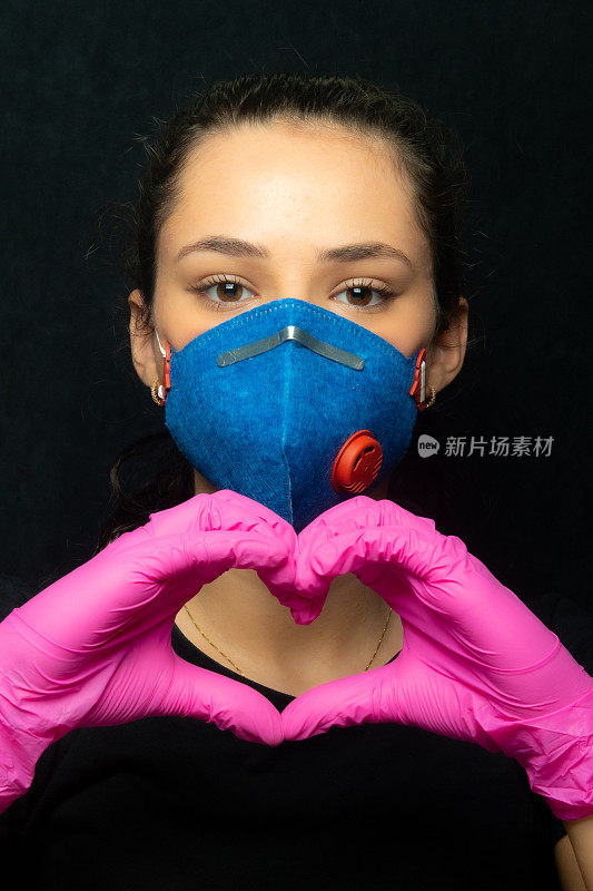 女孩用口罩和手套做一个心形标志-冠状病毒-冠状病毒19