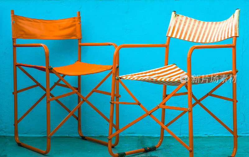 五颜六色的旧条纹橙和白色沙滩椅在蓝色的墙