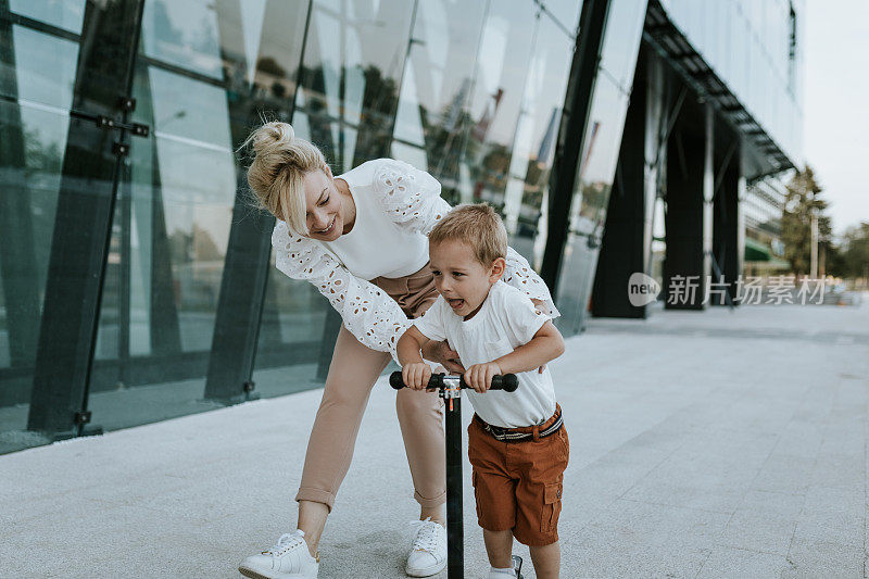 妈妈正在教她的儿子如何骑滑板车