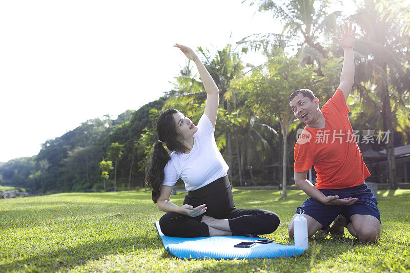 年轻的亚洲孕妇在她丈夫的帮助下做运动