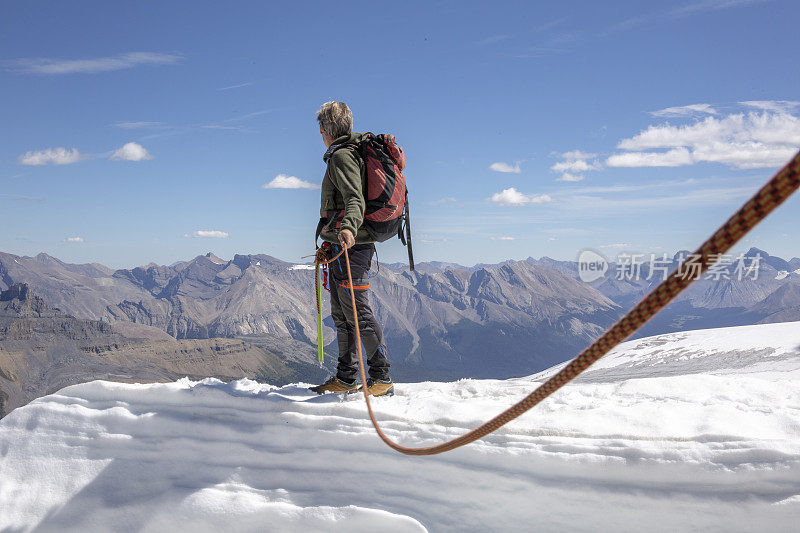 一位男性登山运动员到达了雪山的顶峰