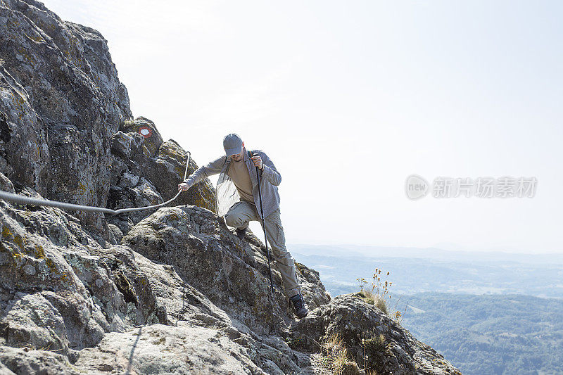 爬山时，男人紧紧抓住绳子