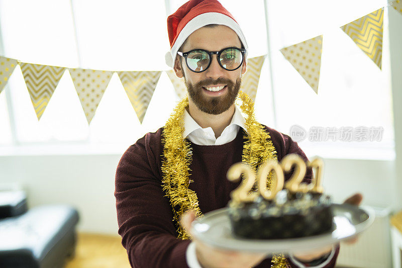 年轻女子在新年派对上玩得很开心，巧克力蛋糕上写着蜡烛数字2021，代表即将到来的新年