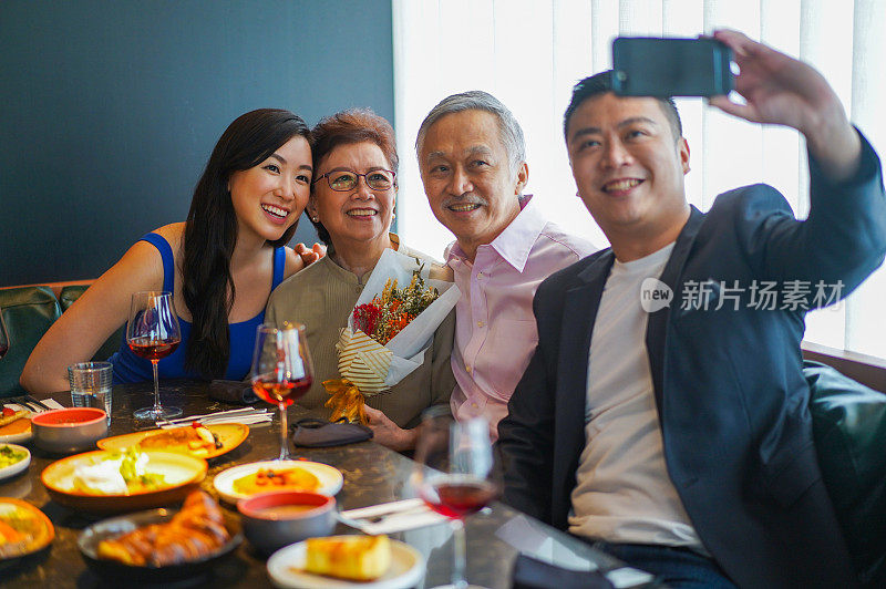 亚洲家庭在餐桌上用手机自拍。