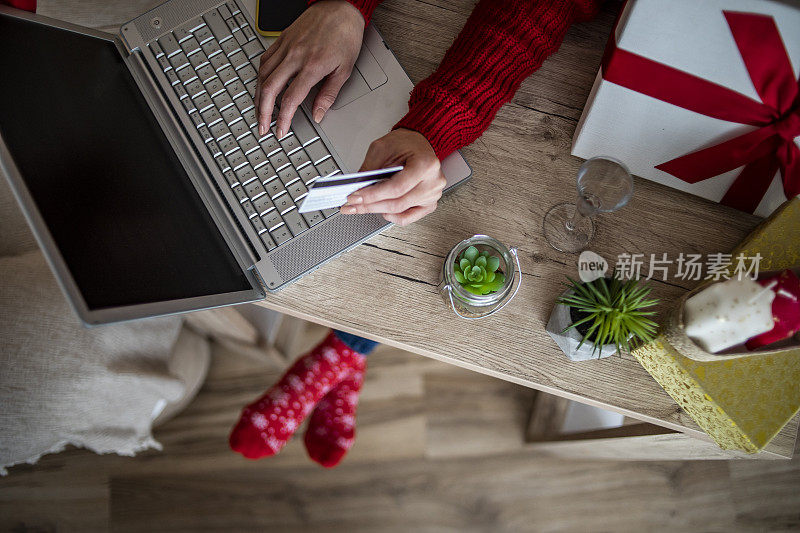 女人用信用卡在家里买新年的礼物-圣诞购物-一个年轻女人在网上买礼物的特写