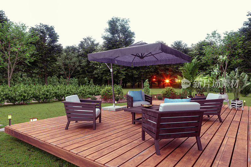 庭院与木制座椅，咖啡桌和遮阳板在花园日落的背景。