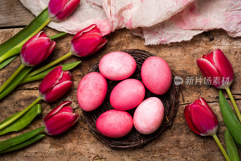 复活节彩蛋与红色郁金香花排列平放在木桌上