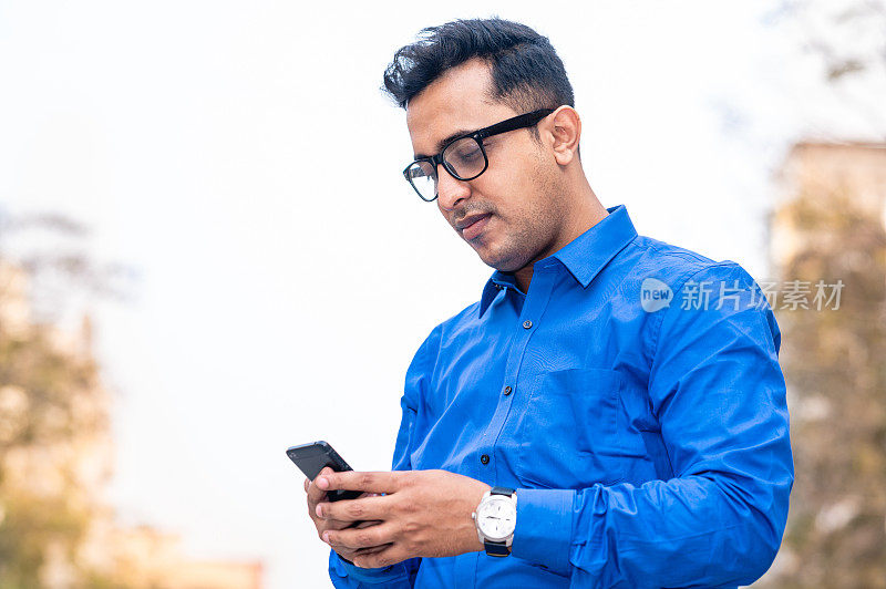 一个戴着眼镜拿着智能手机的商人的肖像。