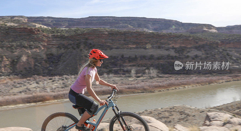 女性山地自行车在早上遵循沙漠路径