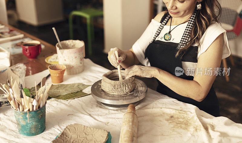 女性陶瓷艺术家雕刻粘土和制作碗。