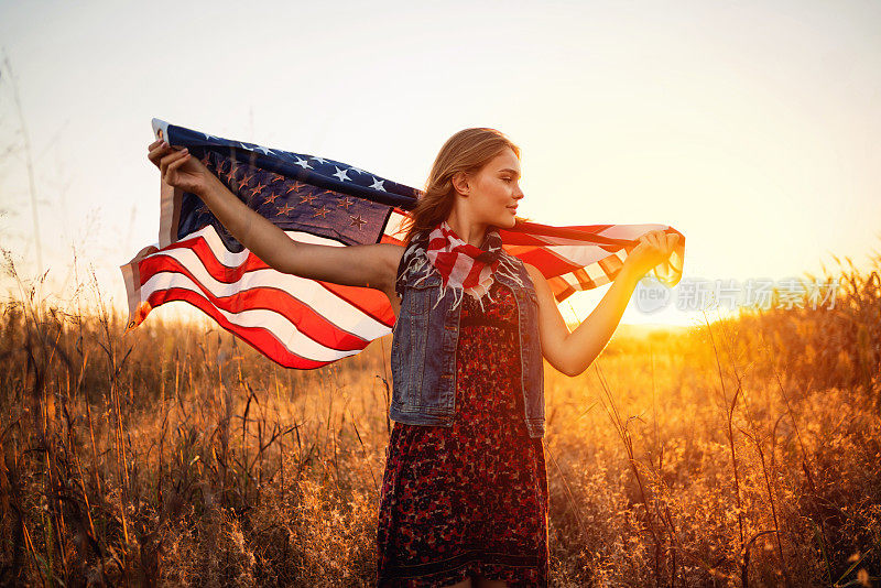 一个在户外举着美国国旗的年轻女人