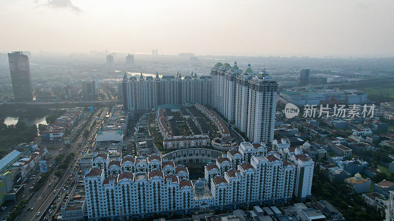城市新绿城市景观鸟瞰图。城市景观的住宅区与现代公寓建筑日落时与噪音云。印度尼西亚雅加达，2022年6月23日