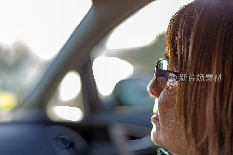 日落时分乘车旅行。这是一个戴着眼镜的女人透过前挡风玻璃看风景的特写镜头