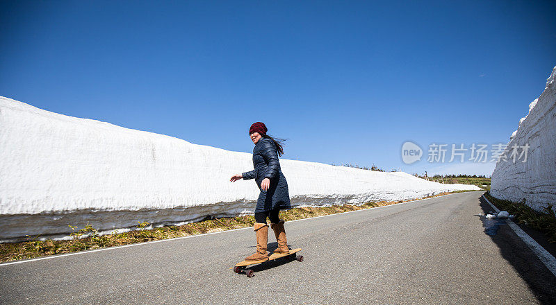 女滑板沿着高高的雪墙的山路