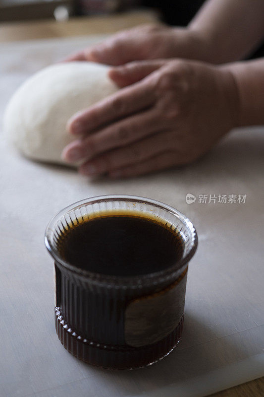 咖啡杯放在面包师的桌子上，一边揉面团